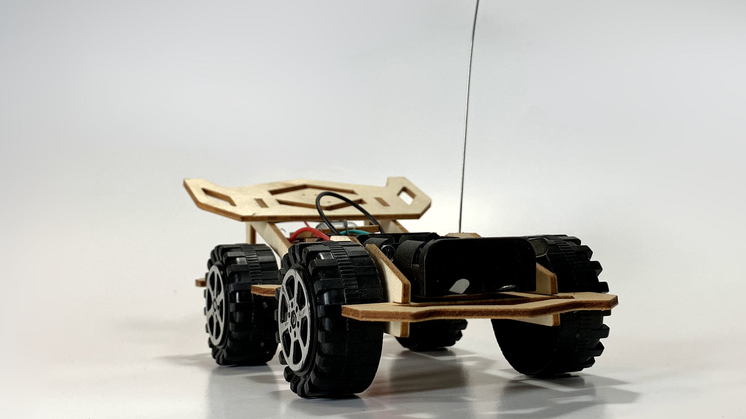 Remote Control Race Car STEM Kit rear view showing rugged wheels, wooden frame, visible wiring, and antenna for remote control functionality