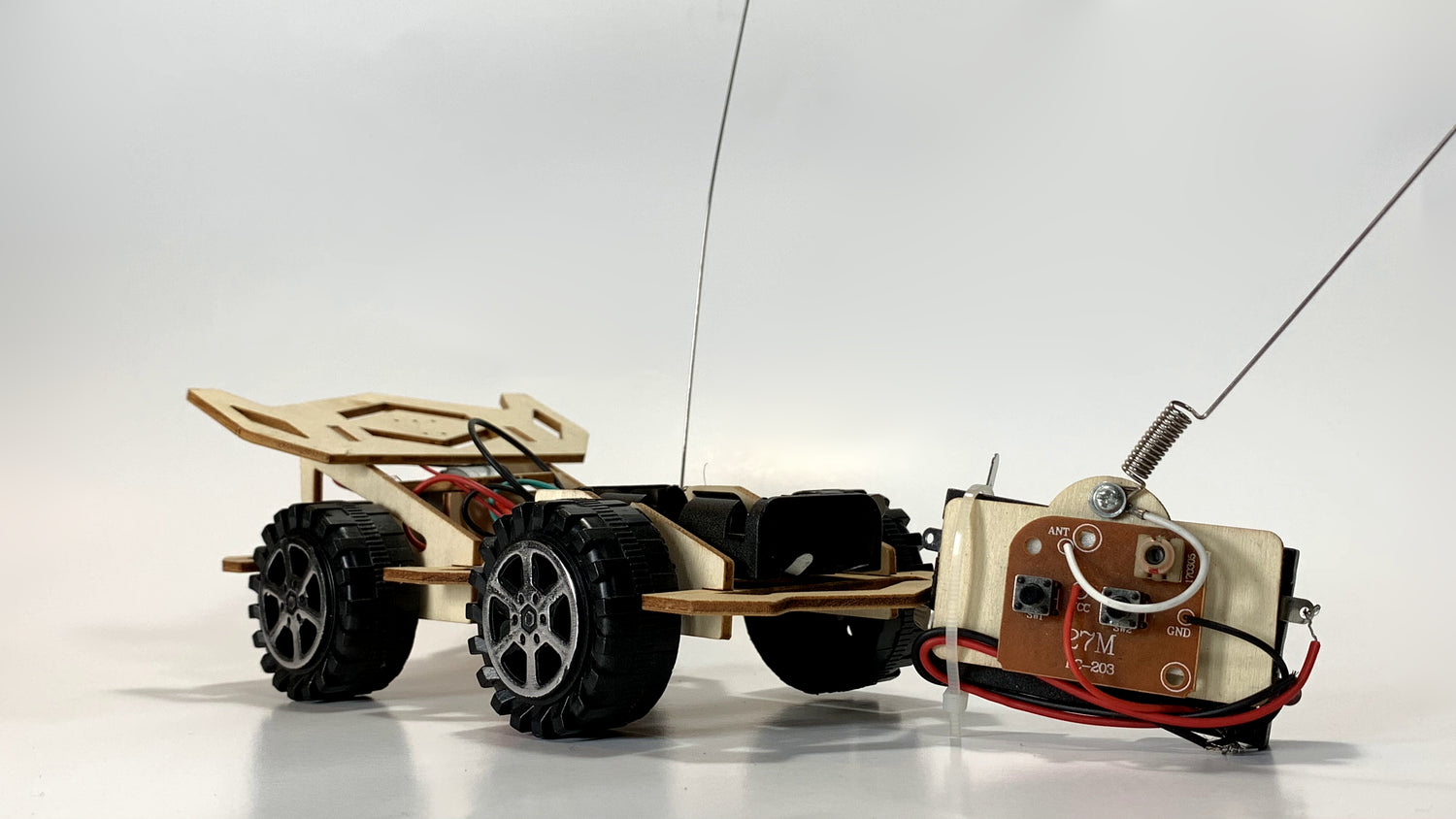 Remote Control Race Car STEM Kit showcasing detailed wiring, wooden chassis, rugged wheels, and a separate circuit module with antenna