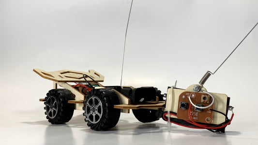 Remote Control Race Car STEM Kit showcasing detailed wiring, wooden chassis, rugged wheels, and a separate circuit module with antenna