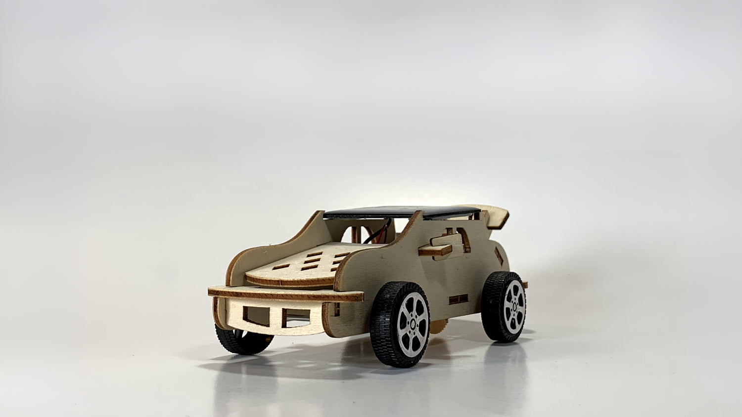 Side angled view of the Solar-Powered Race Car STEM Kit, showcasing wooden construction, solar panel on the roof, and durable black wheels